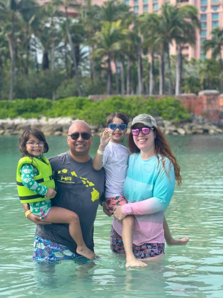 Breast cancer survivor Ashley and her husband and kids smile while on vacation. 
