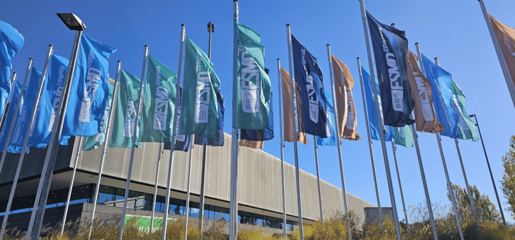 Colorful flags with “ESMO” on them wave in the wind