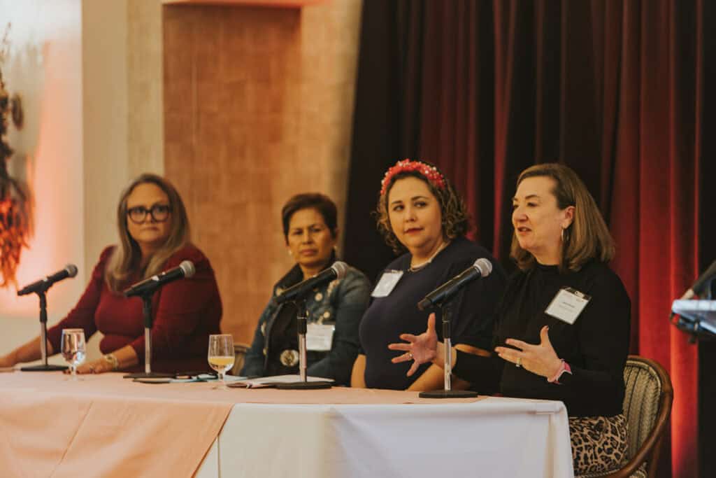 Four women sit at a table at the Susan G. Komen EmpowerED Education After Diagnosis event. The woman on the far right is speaking and the other three women are watching her.