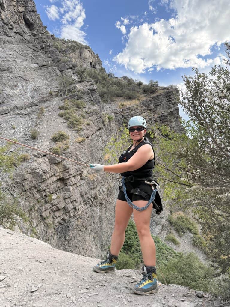 Breast cancer survivor Sara is rappelling outside.
