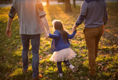 Family walking outdoors holding hands, promoting breast cancer awareness and community support.