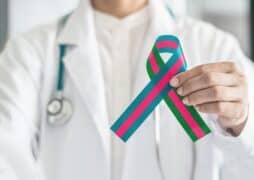 A doctor holds up a metastatic breast cancer ribbon.