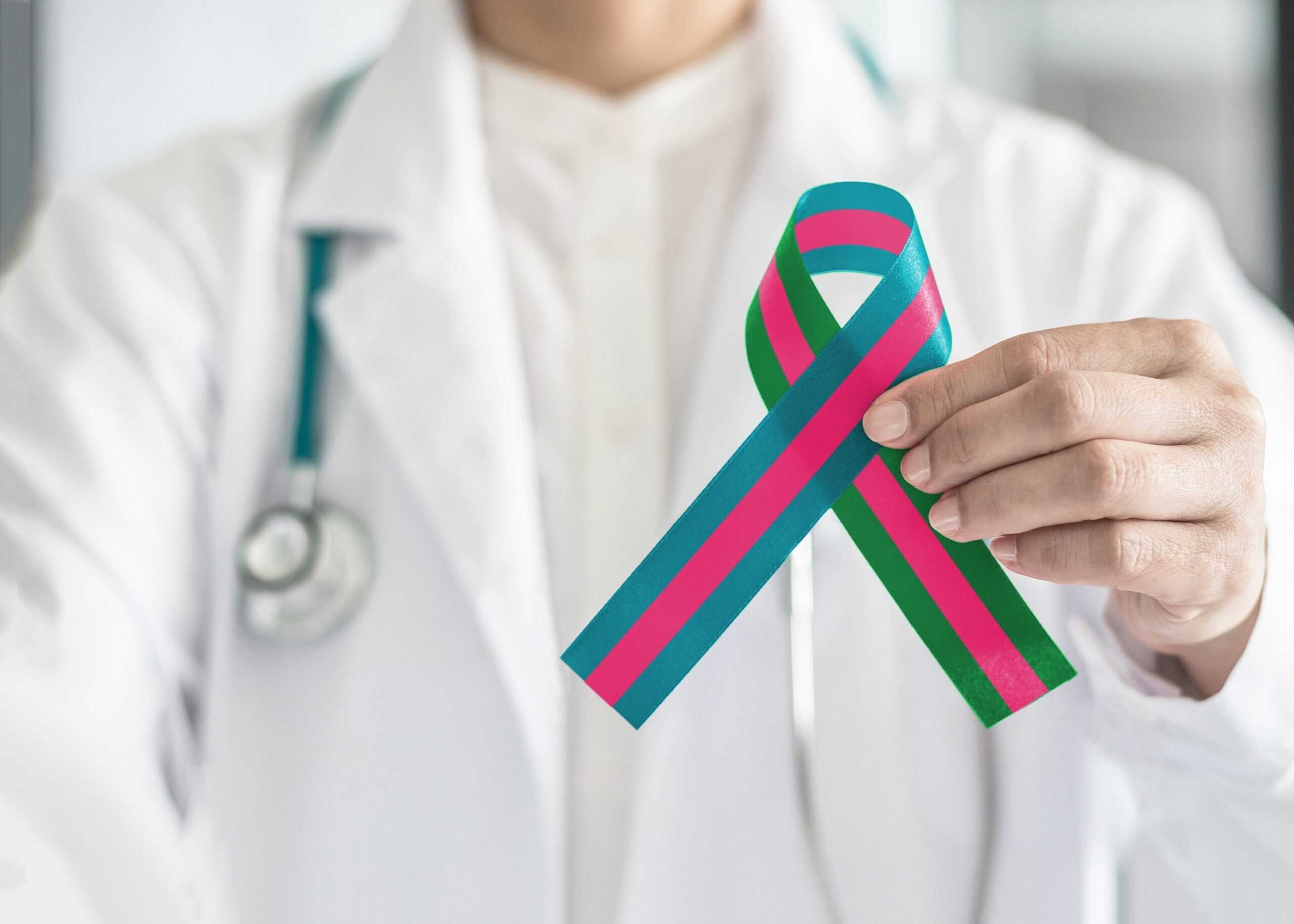 A doctor holds up a metastatic breast cancer ribbon.